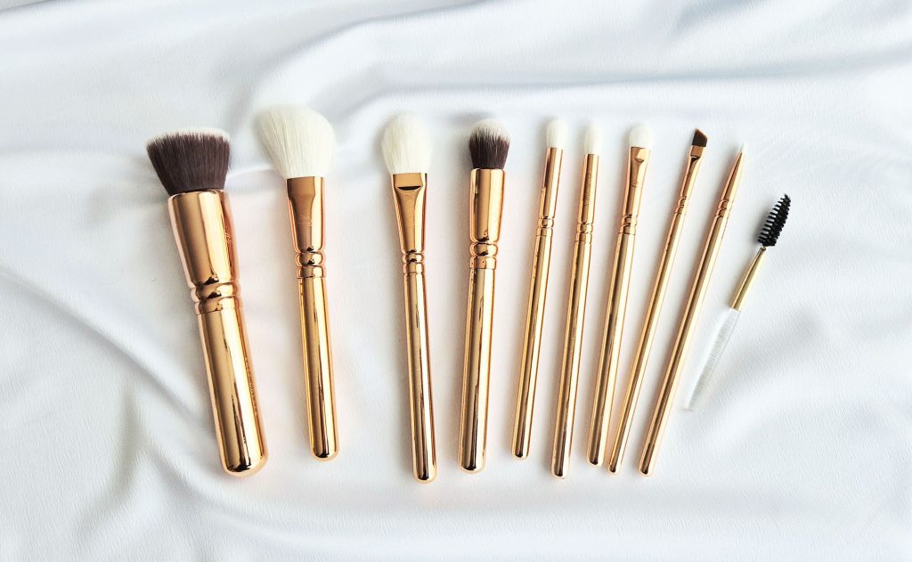 Vue d'ensemble d'un kit de 10 pinceaux de maquillage Zoeva rose gold disposés sur un tissu blanc satiné.