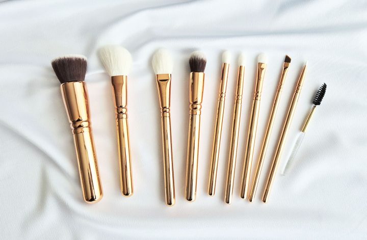 Vue d'ensemble d'un kit de 10 pinceaux de maquillage Zoeva rose gold disposés sur un tissu blanc satiné.