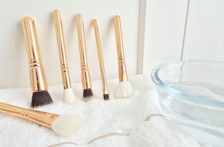 Pinceaux de maquillage à nettoyer avec un bol d’eau et une serviette propre