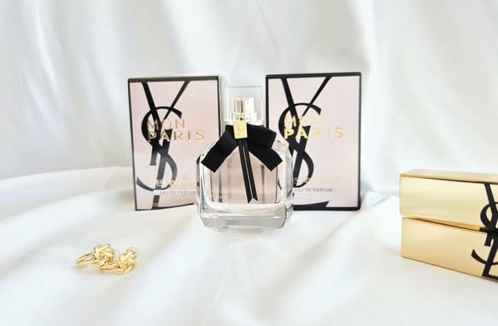 Flacon du parfum Mon Paris Yves Saint Laurent avec boîte et accessoires sur fond blanc élégant