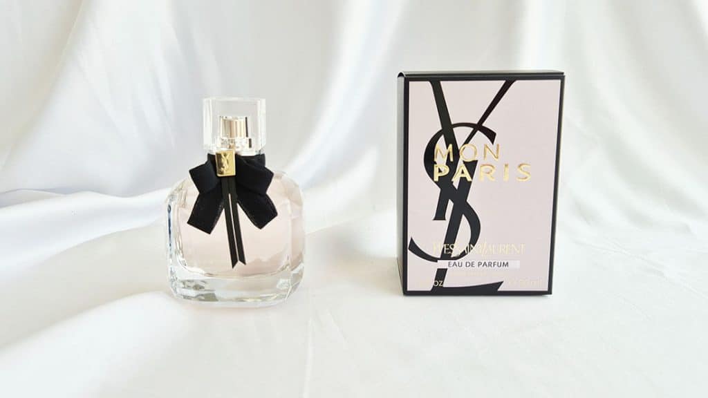 Flacon Mon Paris Yves Saint Laurent posé à côté de sa boîte rose avec logo YSL