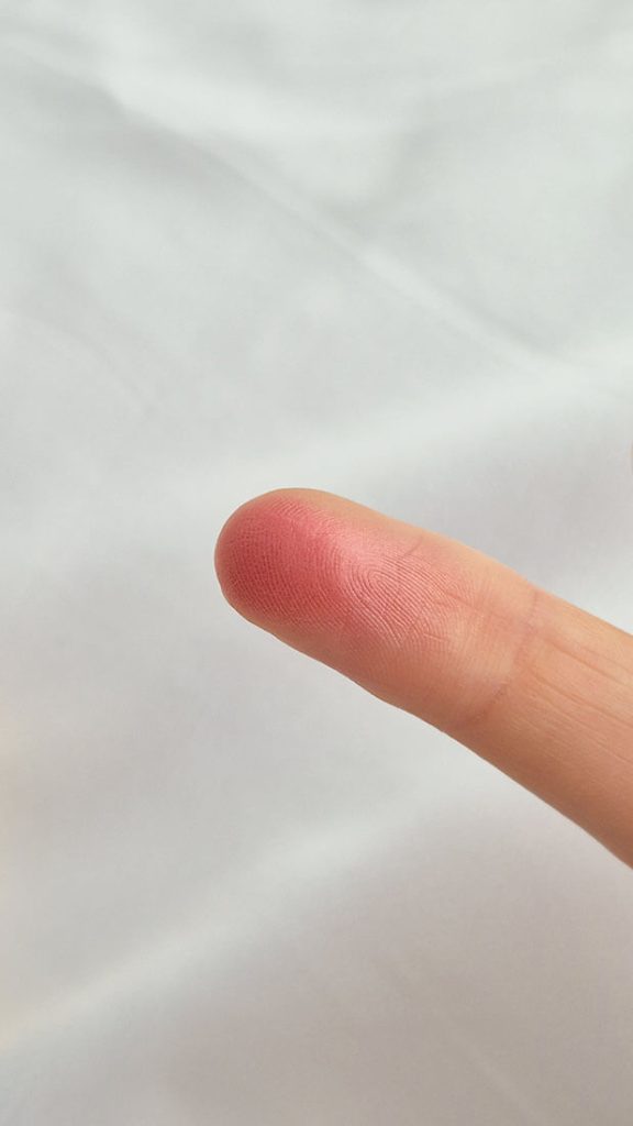Swatch de la texture du Gucci Glow Blush Fresh Coral (02) sur un doigt