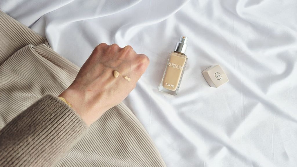 Une pompe de fond de teint Dior Forever Hydra Nude déposée sur le dos de la main à côté du flacon.