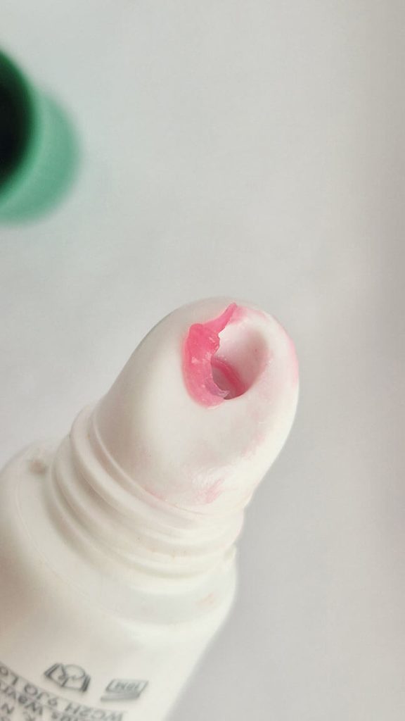 Gros plan sur l'embout biseauté du baume à lèvres Balm Dotcom Glossier teinté rose.