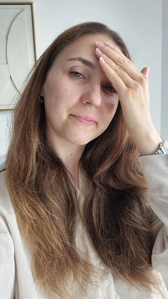 Femme appliquant la crème hydratante La Rosée sur son front du bout des doigts.