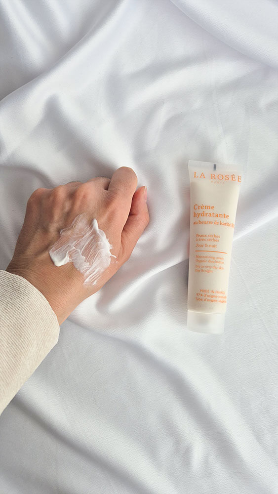 Étalement de la crème riche La Rosée sur le dos de la main montrant une texture fluide et non grasse.