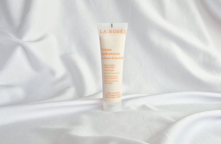 Crème hydratante très riche La Rosée au beurre de karité bio posée sur un tissu blanc
