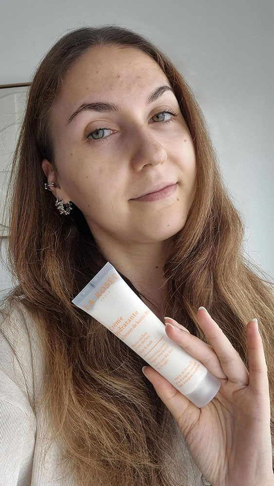 Jeune femme tenant le tube de crème hydratante très riche au beurre de karité bio La Rosée.