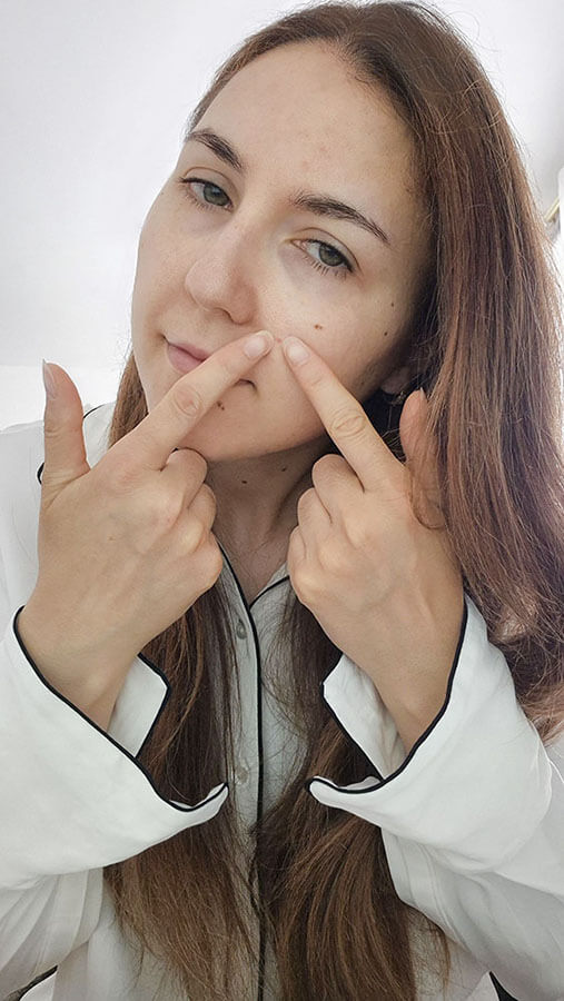 Femme pointant un bouton sur le menton pour illustrer l'erreur de toucher ou percer son acné