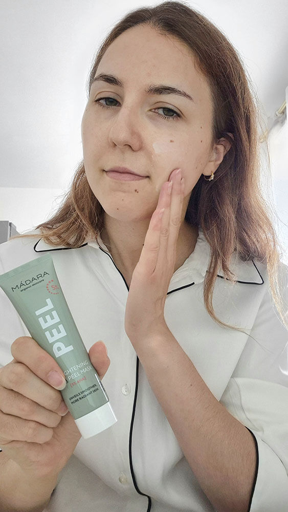 Application d'un masque exfoliant aux AHA Mádara Peel sur le visage pour traiter les imperfections