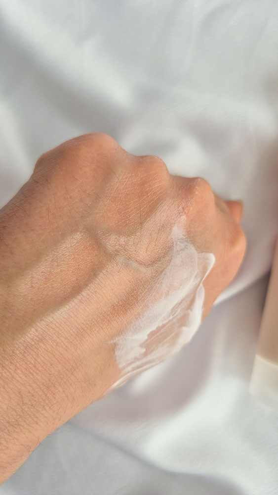 Gros plan sur la peau du dos de la main en train d'absorber la crème hydratante La Rosée.